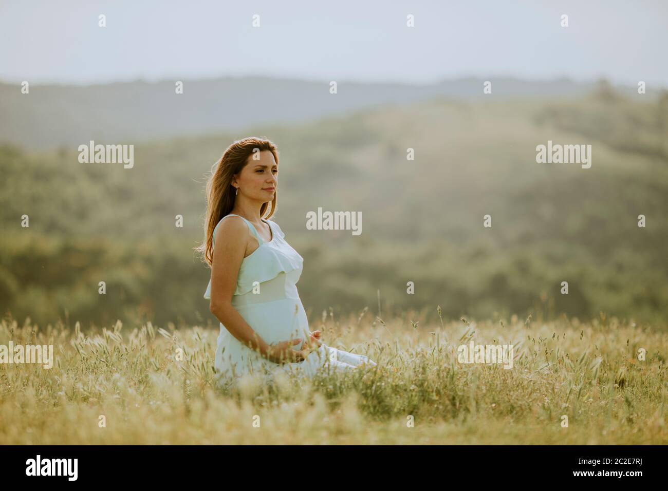 Young pregnant woman in white dress in the summer field Stock Photo - Alamy
