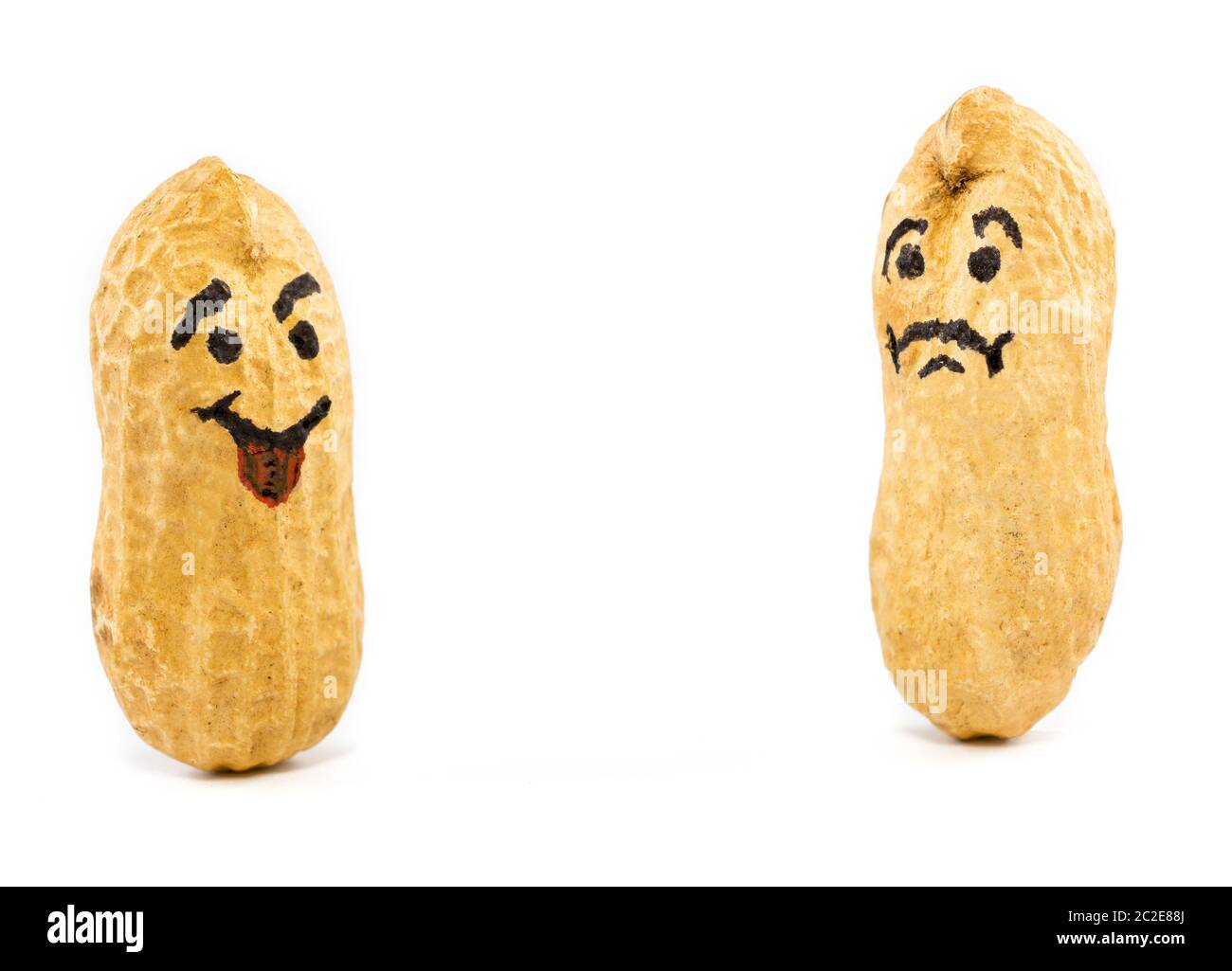 Smile and sad face drawn on dried peanuts on white background. Concept for good mood or bad mood Stock Photo