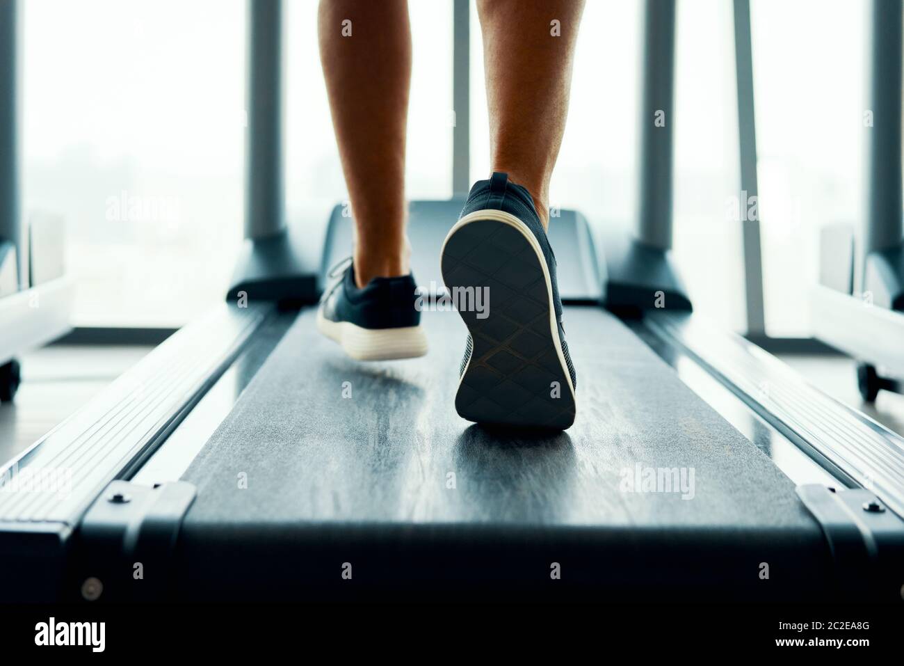 Close up male muscular feet in sneakers running on the treadmill at gym Stock Photo