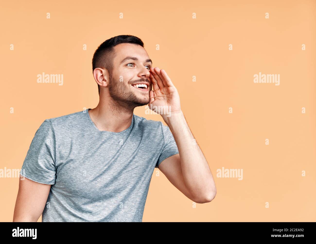 Young handsome man shouting and screaming loud to side with hand on mouth and copy space for text Stock Photo