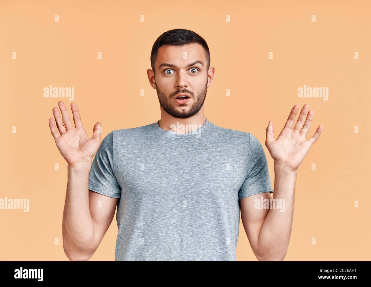 Shocked young man with arms up looking amazed in camera over yellow background Stock Photo Alamy