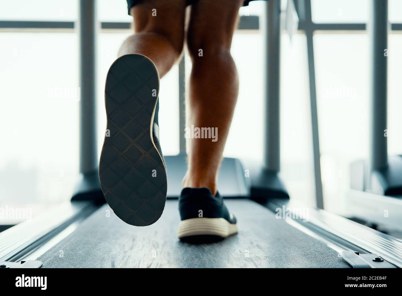 Close up male muscular feet in sneakers running on the treadmill at gym Stock Photo