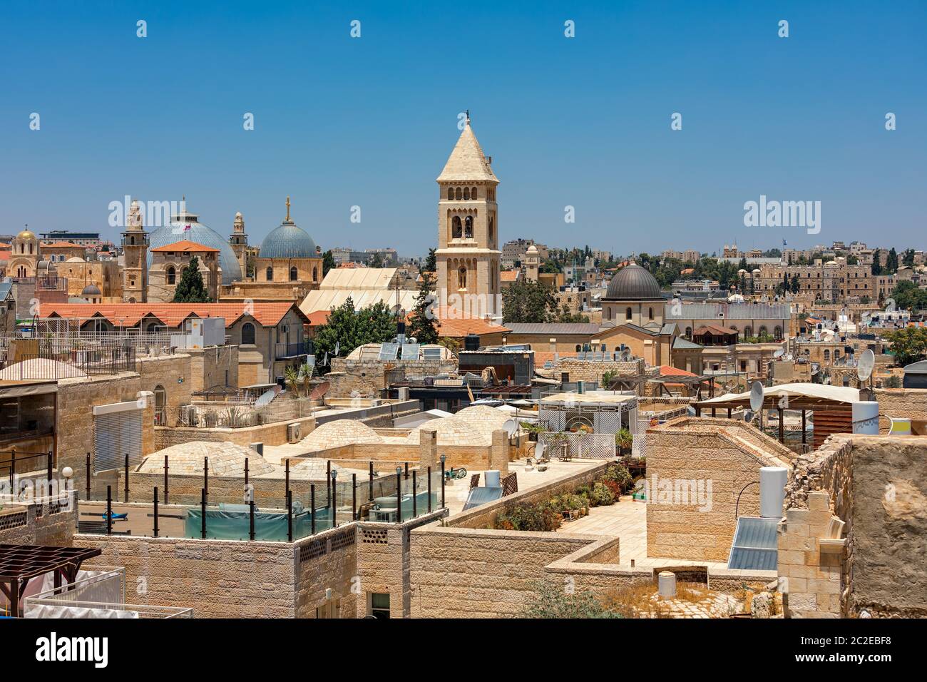 Domes and belfries among typical  stone buildings and rooftops under blue sky in Old City of Jerusalem, Israel. Stock Photo