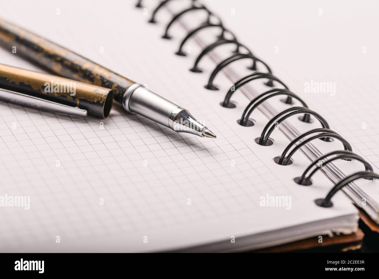 Opened notepad in a cage with an automatic plastic ballpoint pen close-up. Stock Photo