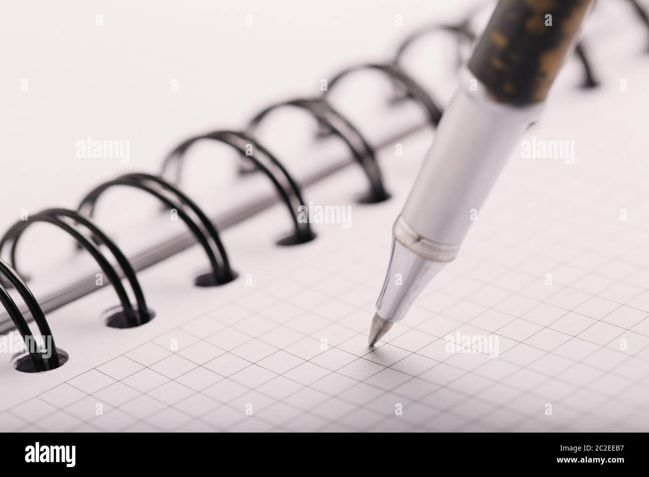 Opened notepad in a cage with an automatic plastic ballpoint pen close-up. Stock Photo