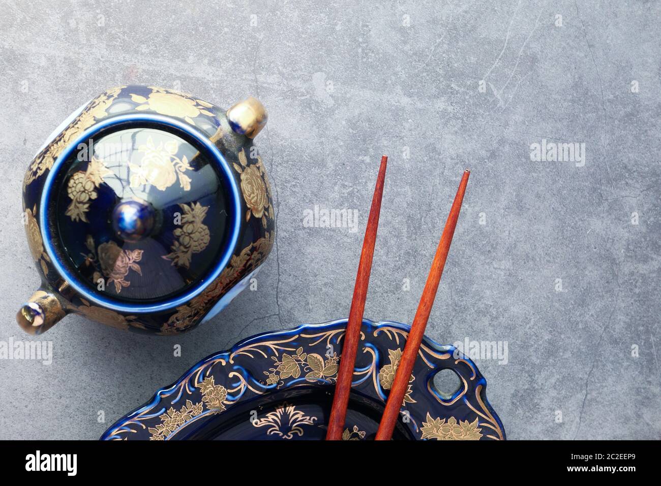 Empty plate, teapot with herbal tea and chopsticks over table Stock Photo