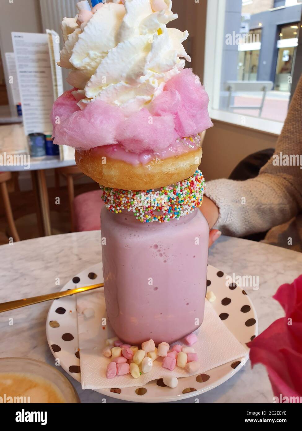 Pink strawberry freakshake with sweets, donuts and wipped cream in cafe, extreme milkshake sugar Stock Photo