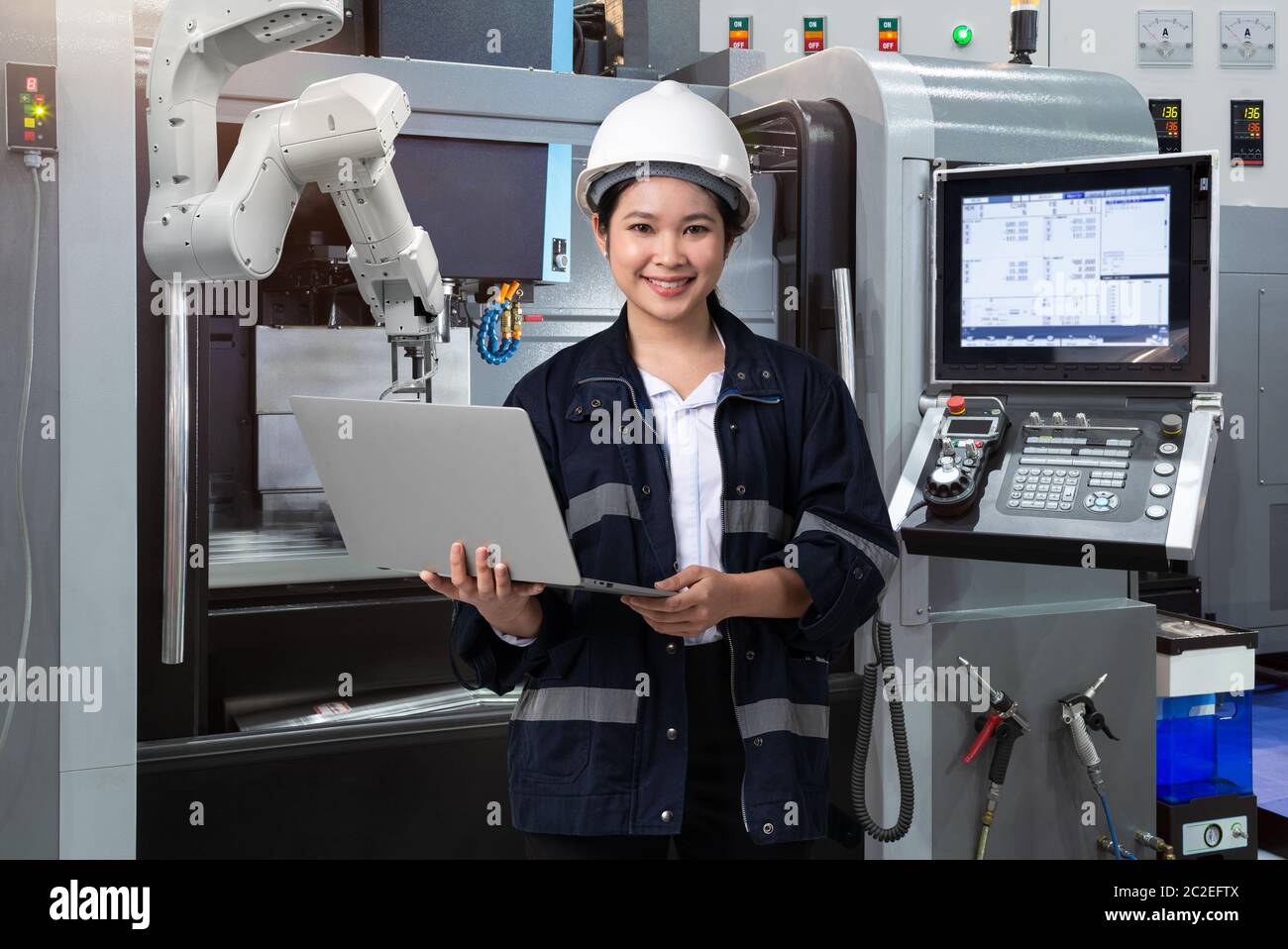 Maintenance female engineer using laptop computer control automatic robotic hand with CNC machine in smart factory, Industry 4.0 concept Stock Photo