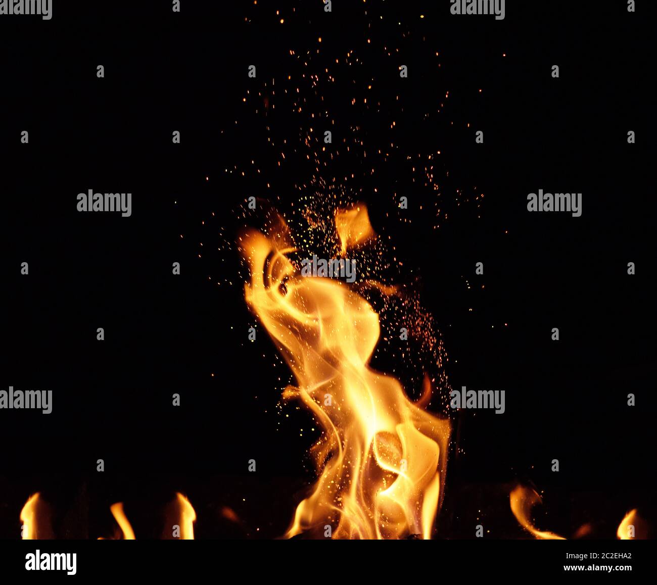 large burning bonfire with flame and orange sparks that fly in different directions on a black background Stock Photo