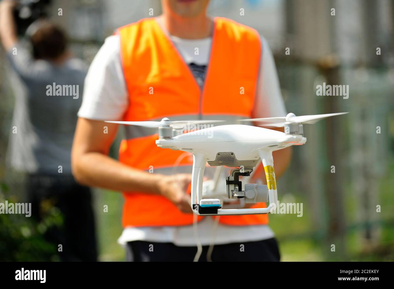 pro quadcopter with camera aboard flying, operator controlling it on the background Stock Photo