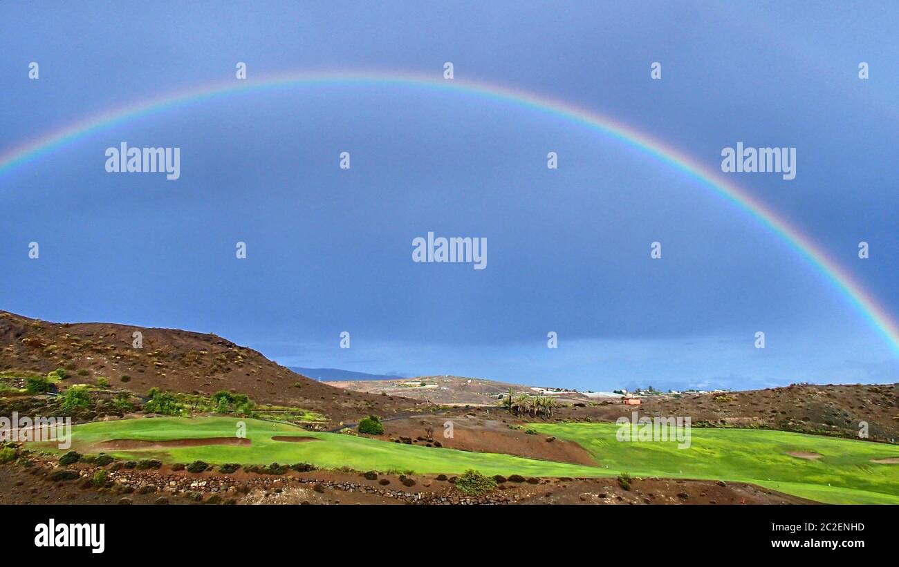 A wonderful colorful rainbow in the blue sky over a green golf course on the Spanish Atlantic island of Gran Canaria Stock Photo