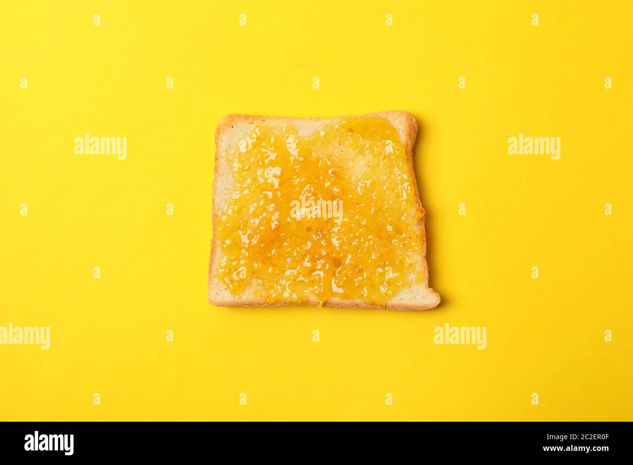 Toast with orange jam on yellow background, close up Stock Photo