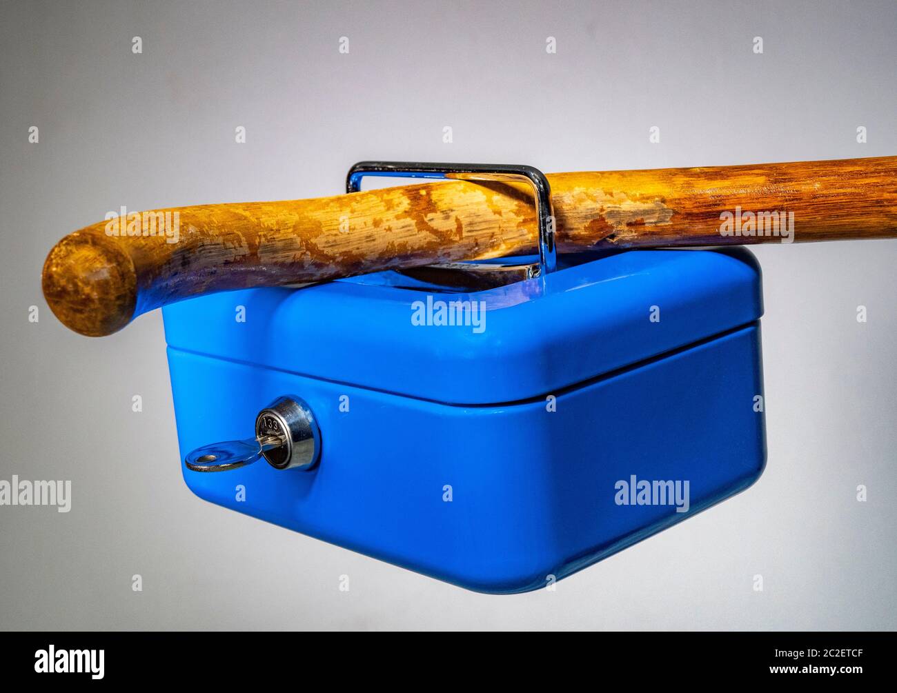 Walking cane through handle of locked box, up in the air – security related concept (money, documents, small valuables) in relation to elderly people. Stock Photo
