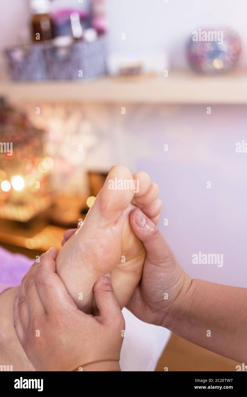 Female therapist giving a foot reflexology massage to a man Stock Photo