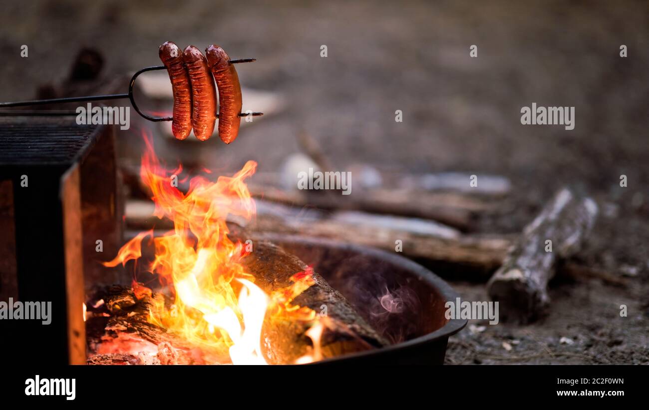 Preparing sausage on campfire, camping dinner Stock Photo