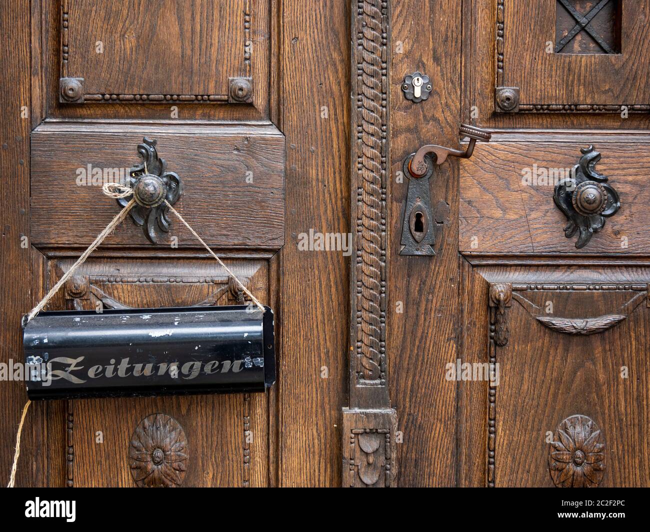 a newspaper mailbox hangs on an old wooden front door Stock Photo