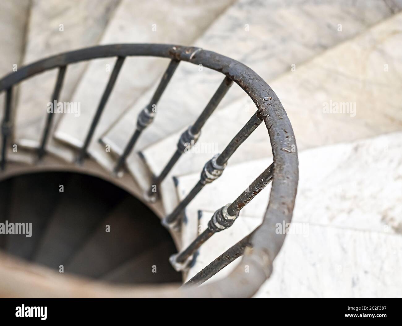 ancient spiral staircase with marble steps and wrought iron handrail. Stock Photo