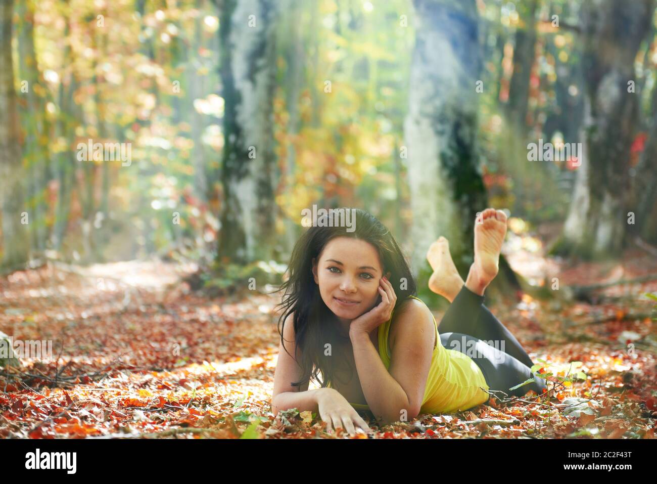 Pretty girl in the autumn forest laying on yellow leaves Stock Photo ...