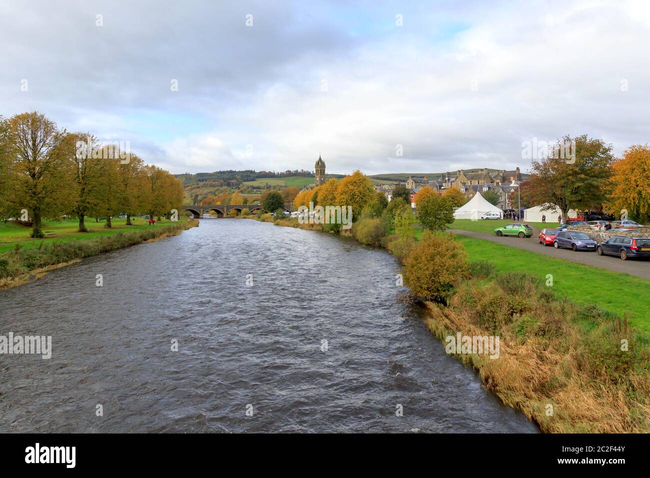 PEEBLES, SCOTLAND - OCTOBER 20, 2019: View down the River Tweed with trees in autumn colour and Peebles Old Parish Church Tower in the distance Stock Photo