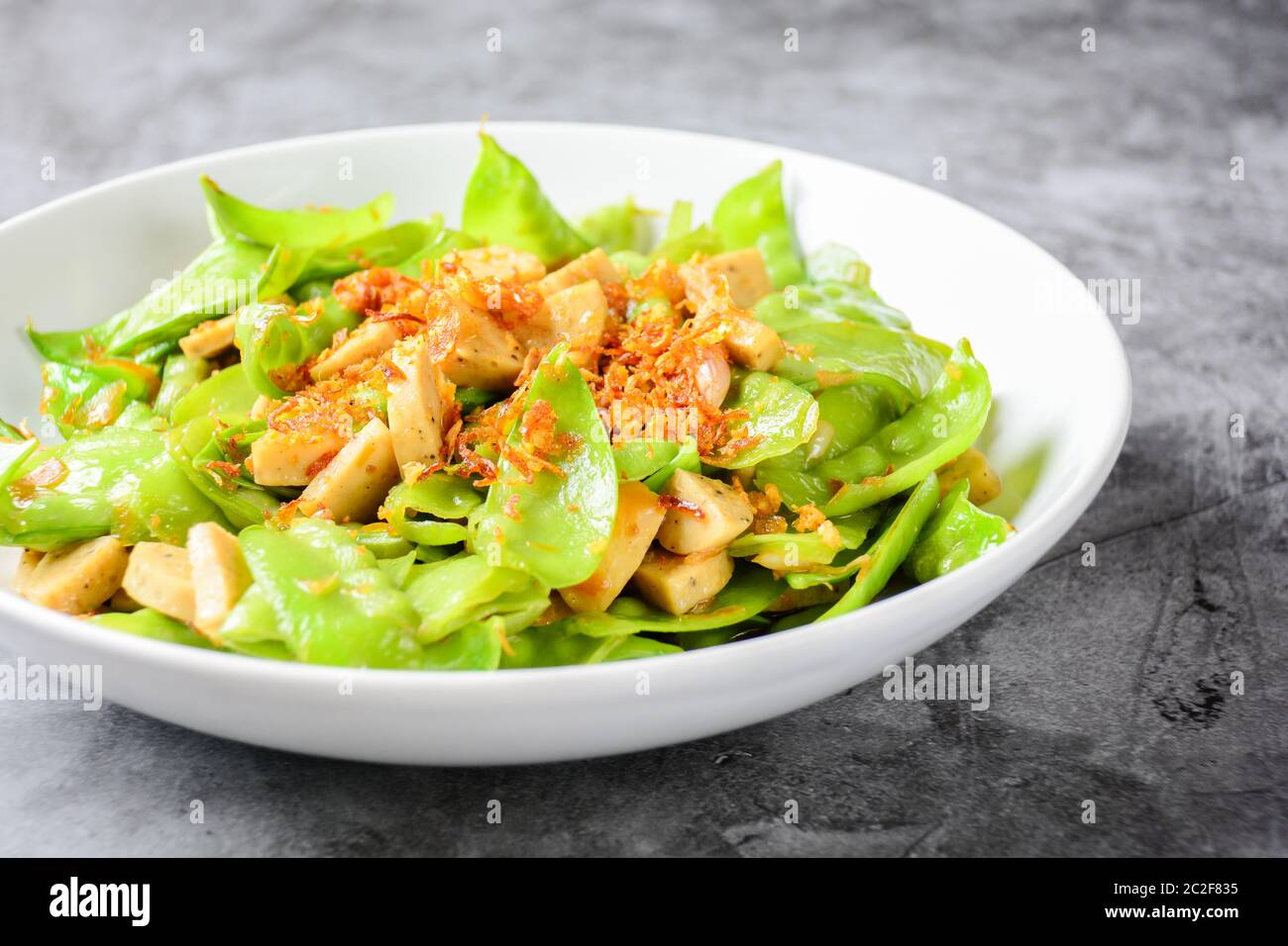 Stir Fry Snow Peas with Vietnamese Grilled Pork Sausage, topping with crispy fried shallots and garl Stock Photo