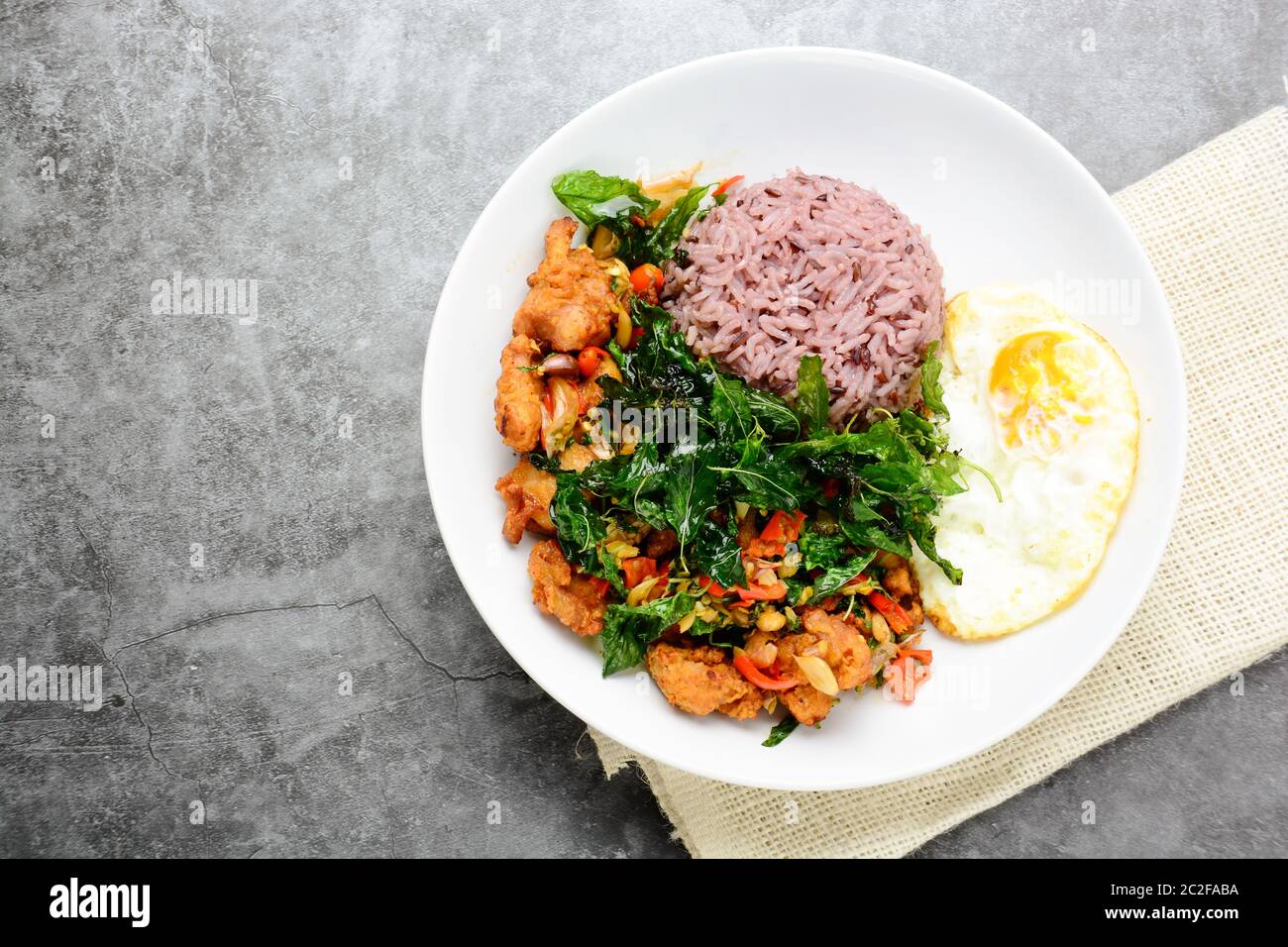 Crispy chicken cooked with green basil, served with steamed rice and fried egg, hot and spicy dish w Stock Photo