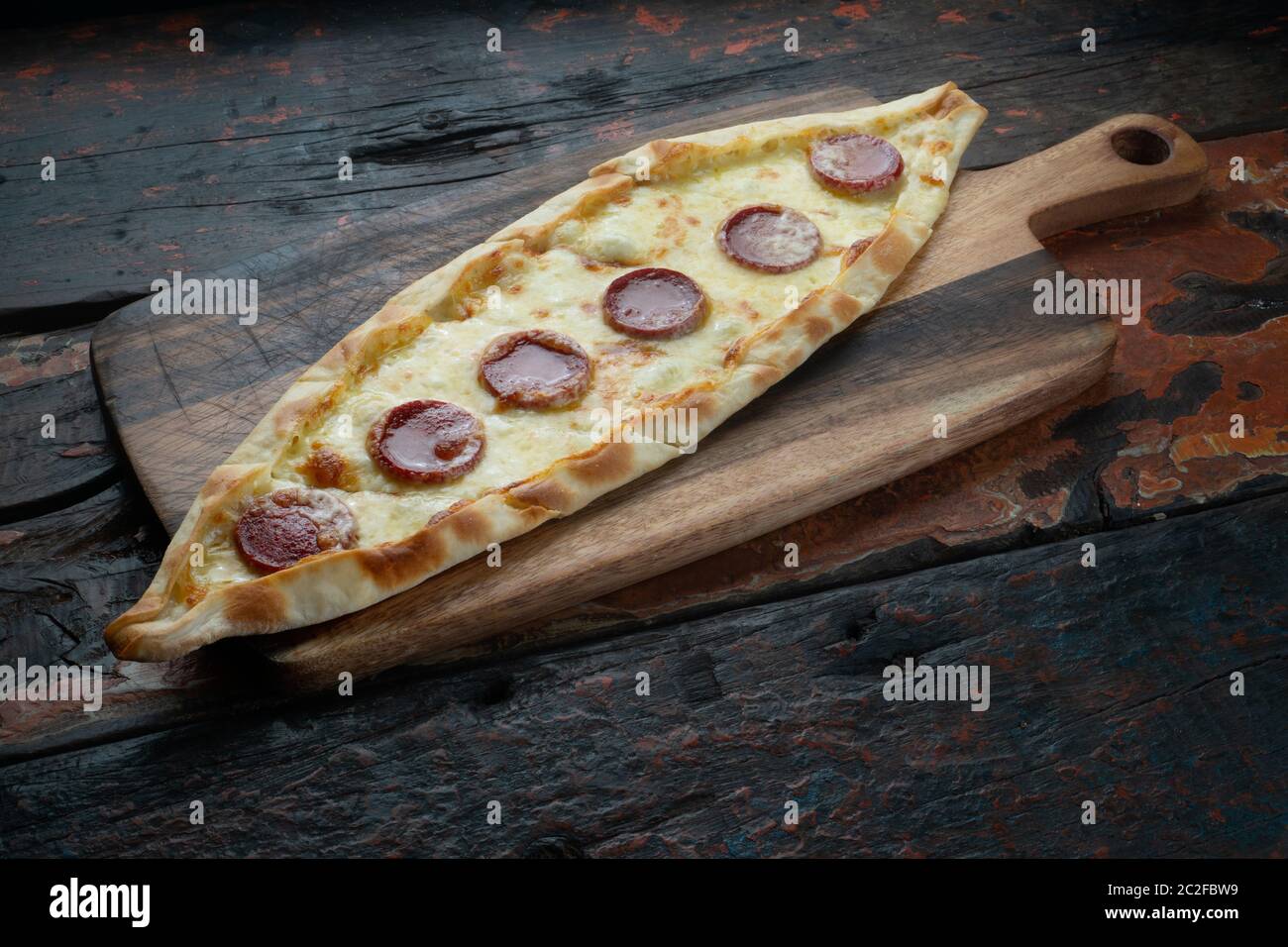 Turkish pide with sausage isolated on rustic wooden table Stock Photo