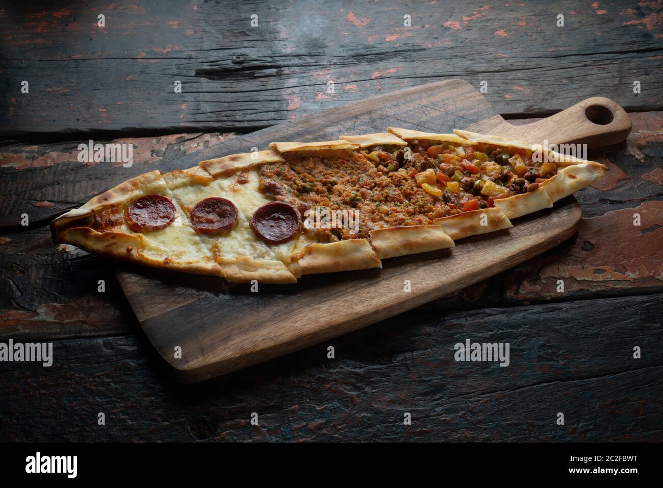 Turkish pide with sausage, beef and vegetables isolated on rustic wooden table Stock Photo
