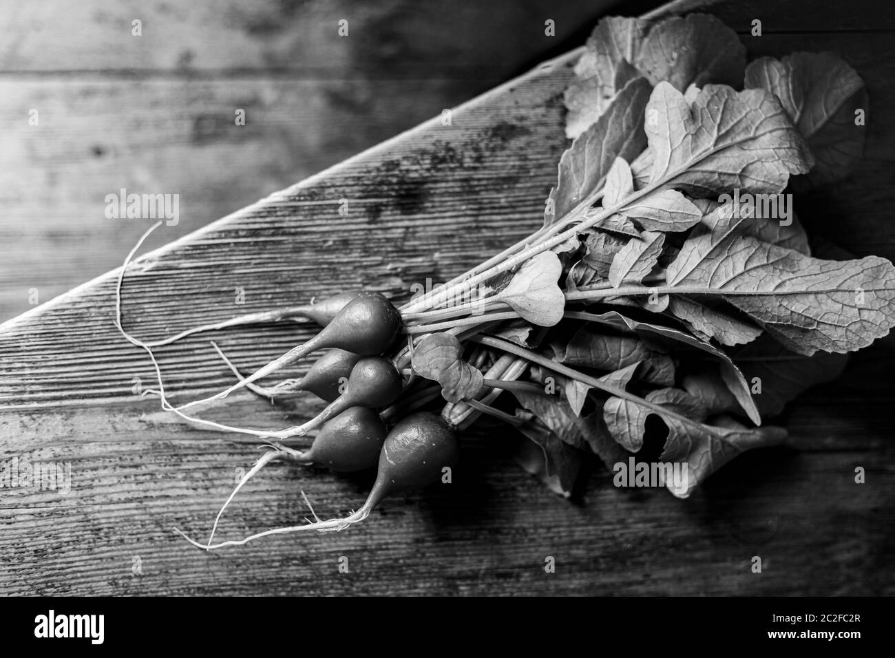 Red radish on a wooden table. Red vegetable with green leaves. Stock Photo