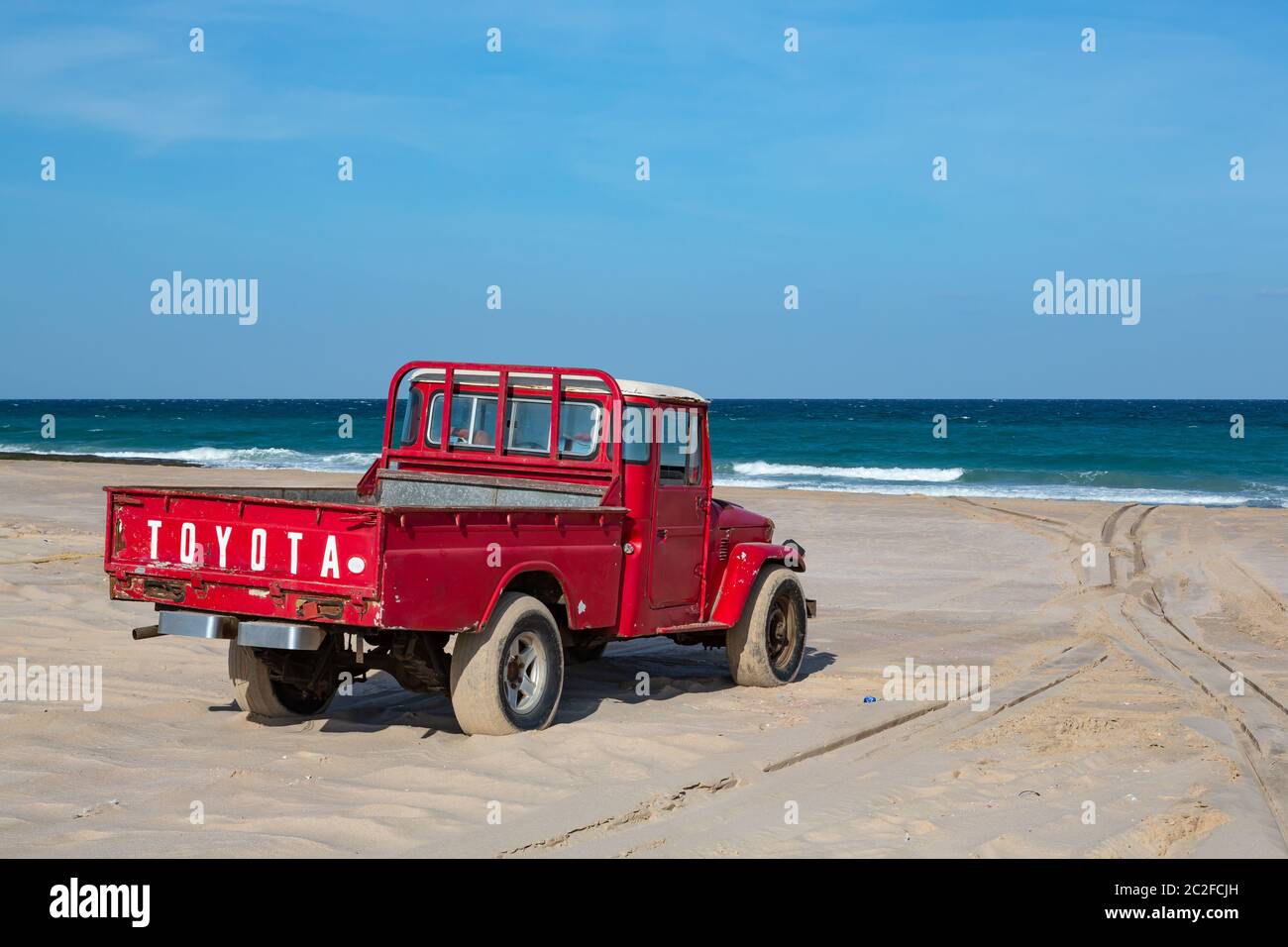 Old red Toyota pick-up truck on Ras al Hadd beach in Oman Stock Photo