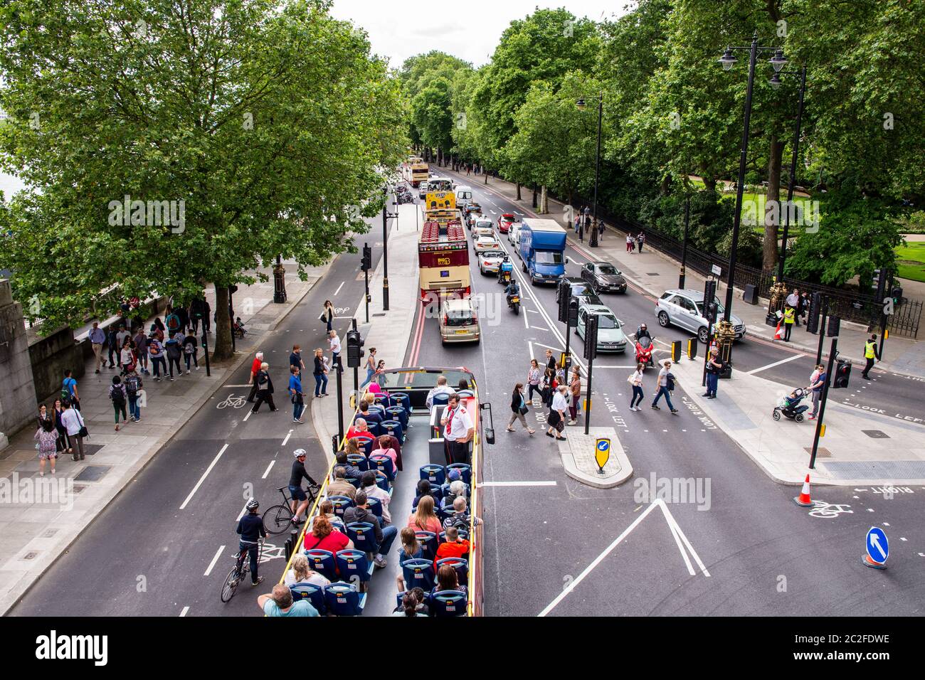 Pedestrians cross Embankment, while a tour bus and other traffic waits, in Westminster in central London. Stock Photo
