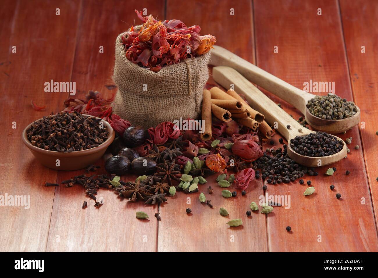 Dried Spices Black pepper,Green pepper,Mace or Javiithri flower,Nutmeg,Clove,Cinnamon,Cardamom,Star Anise arranged on a wooden surface Stock Photo