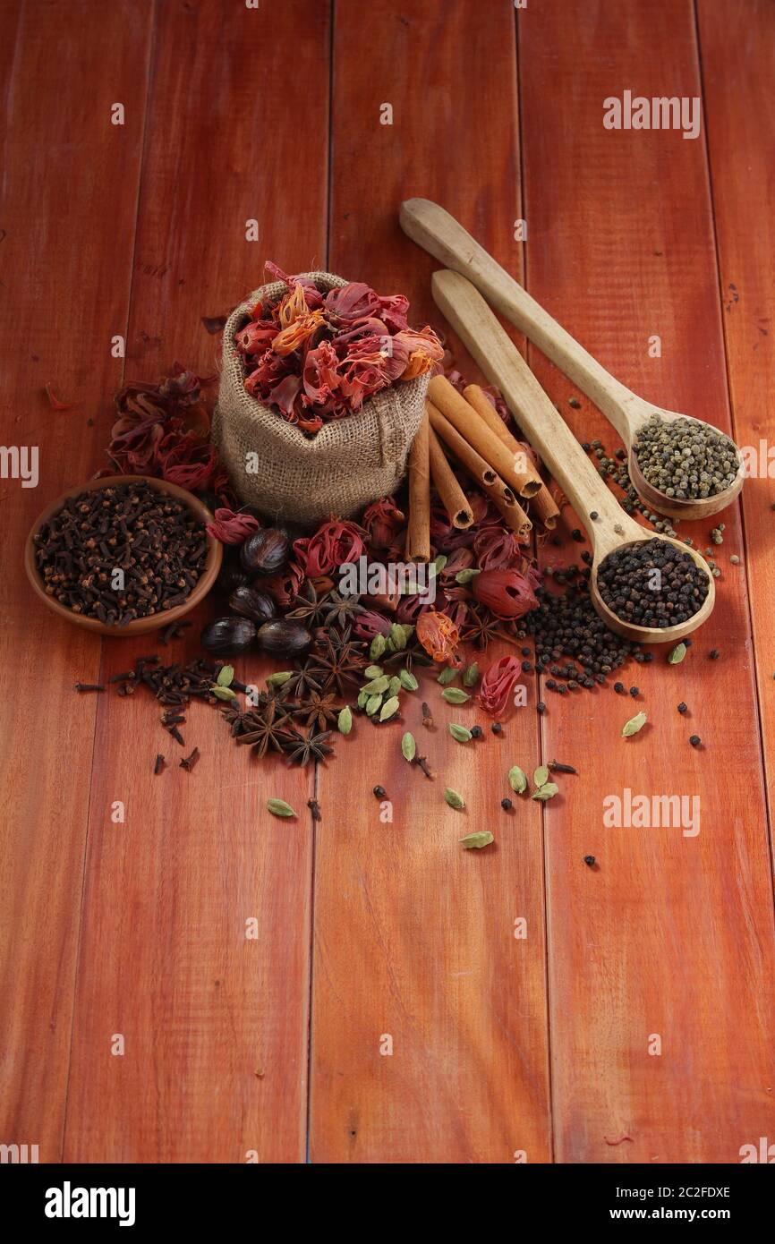 Dried Spices Black pepper,Green pepper,Mace or Javiithri flower,Nutmeg,Clove,Cinnamon,Cardamom,Star Anise arranged on a wooden surface Stock Photo
