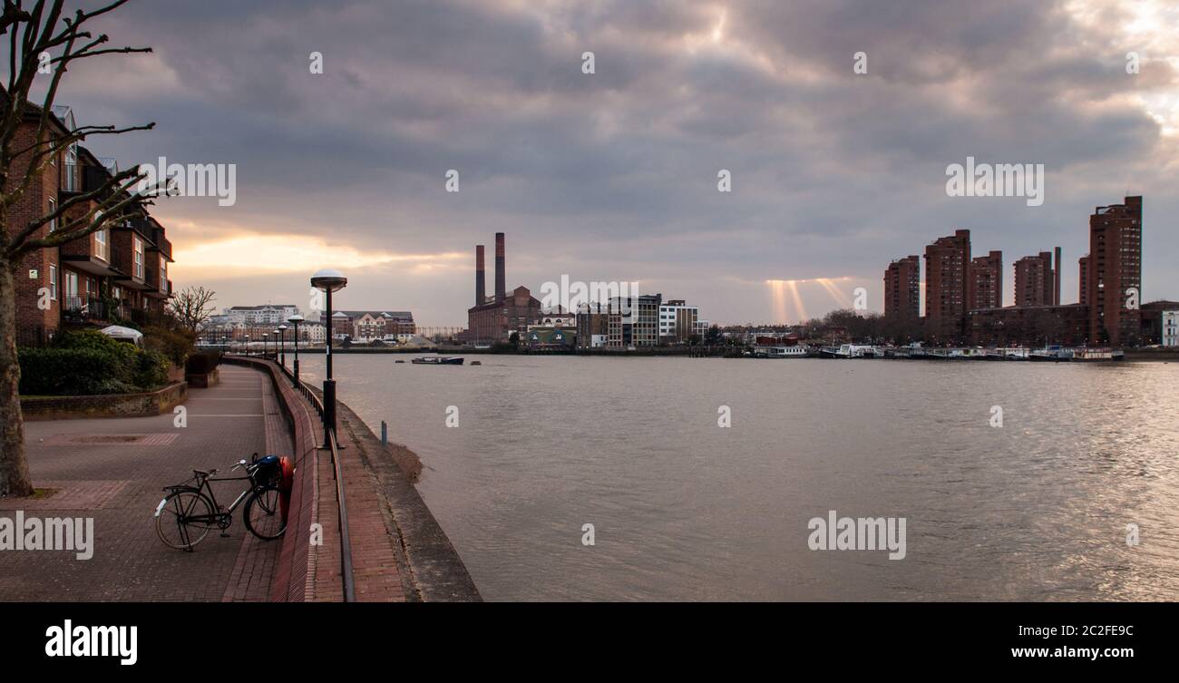 Sunbeams break through clouds above Lots Road Power Station and the World's End Estate on Chelsea's River Thames waterfront in West London. Stock Photo