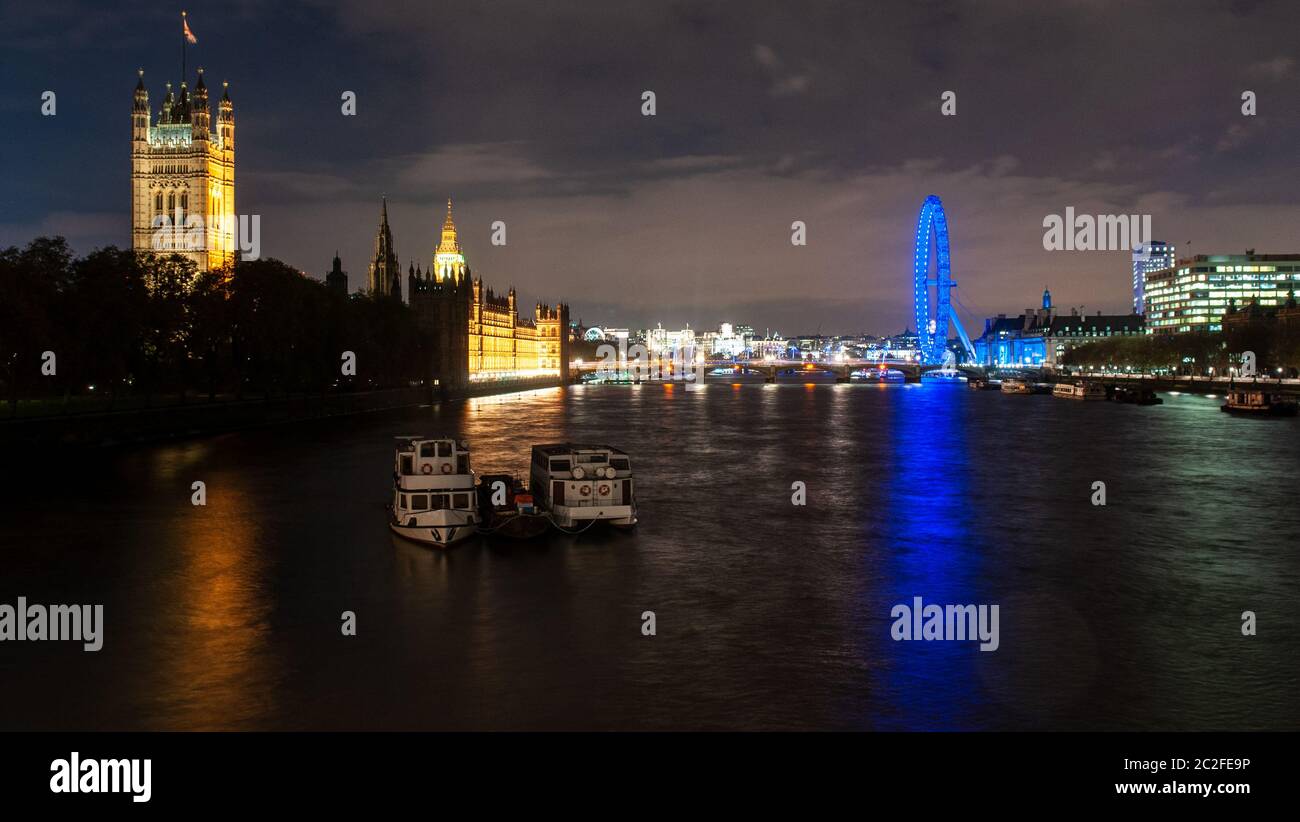 London, England, UK - November 9, 2012: The Palace of Westminster and London Eye are lit up at night on the banks of the River Thames in central Londo Stock Photo