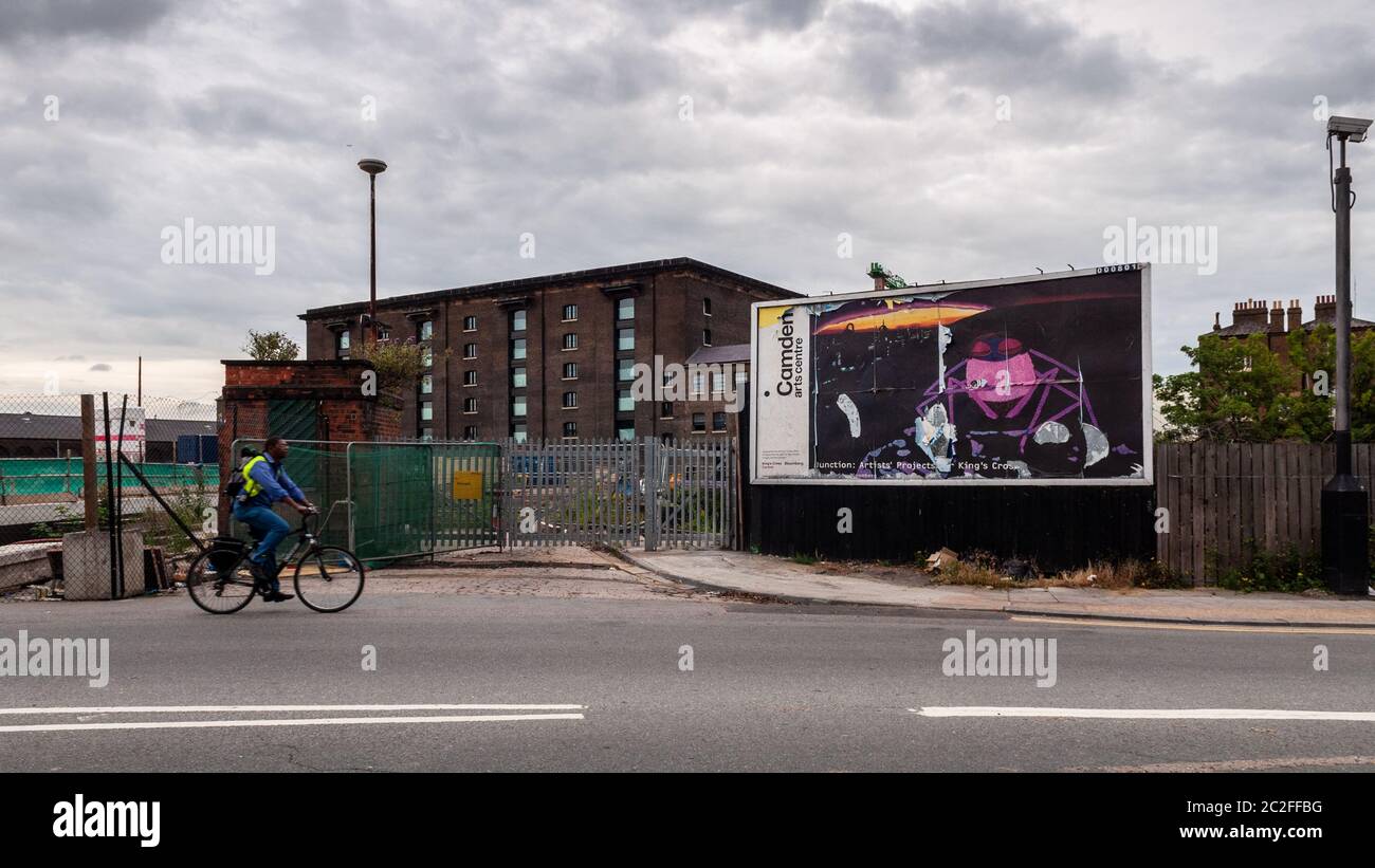 London, England, UK - July 13, 2010: A cyclist rides past a scruffy billboard and wasteground behind King's Cross Station during regeneration of the G Stock Photo