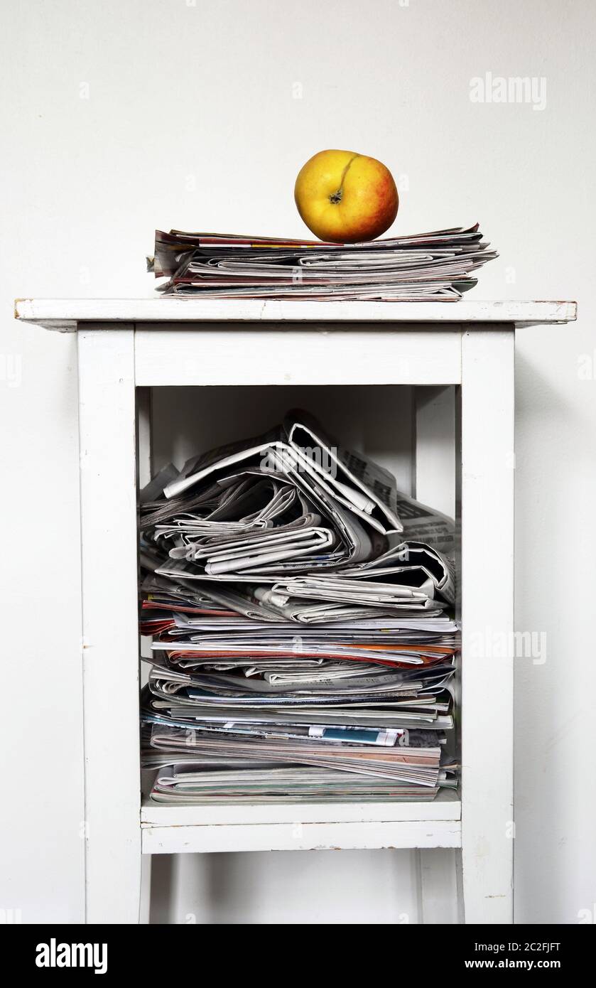 stack of newspapers on the nightstand and an apple Stock Photo
