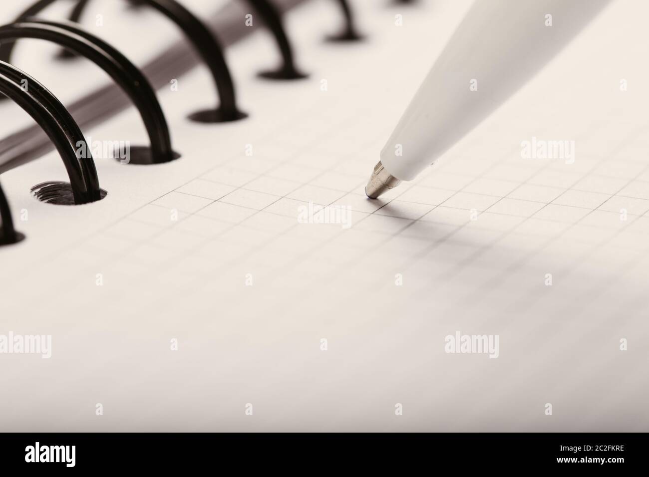 Opened notepad in a cage with an automatic plastic ballpoint pen close-up. Stock Photo