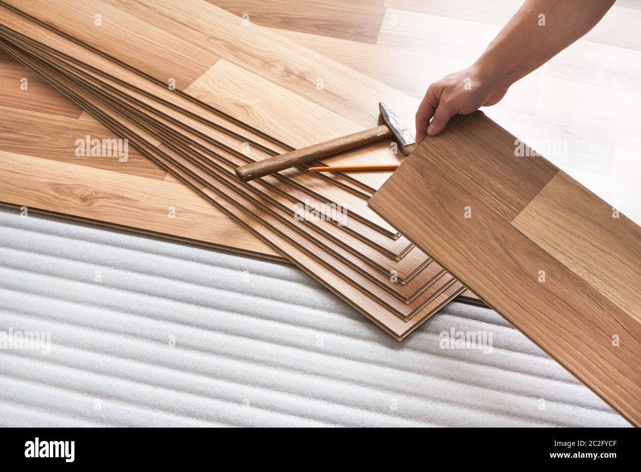 Installing laminated floor, detail on man hands holding wooden tile