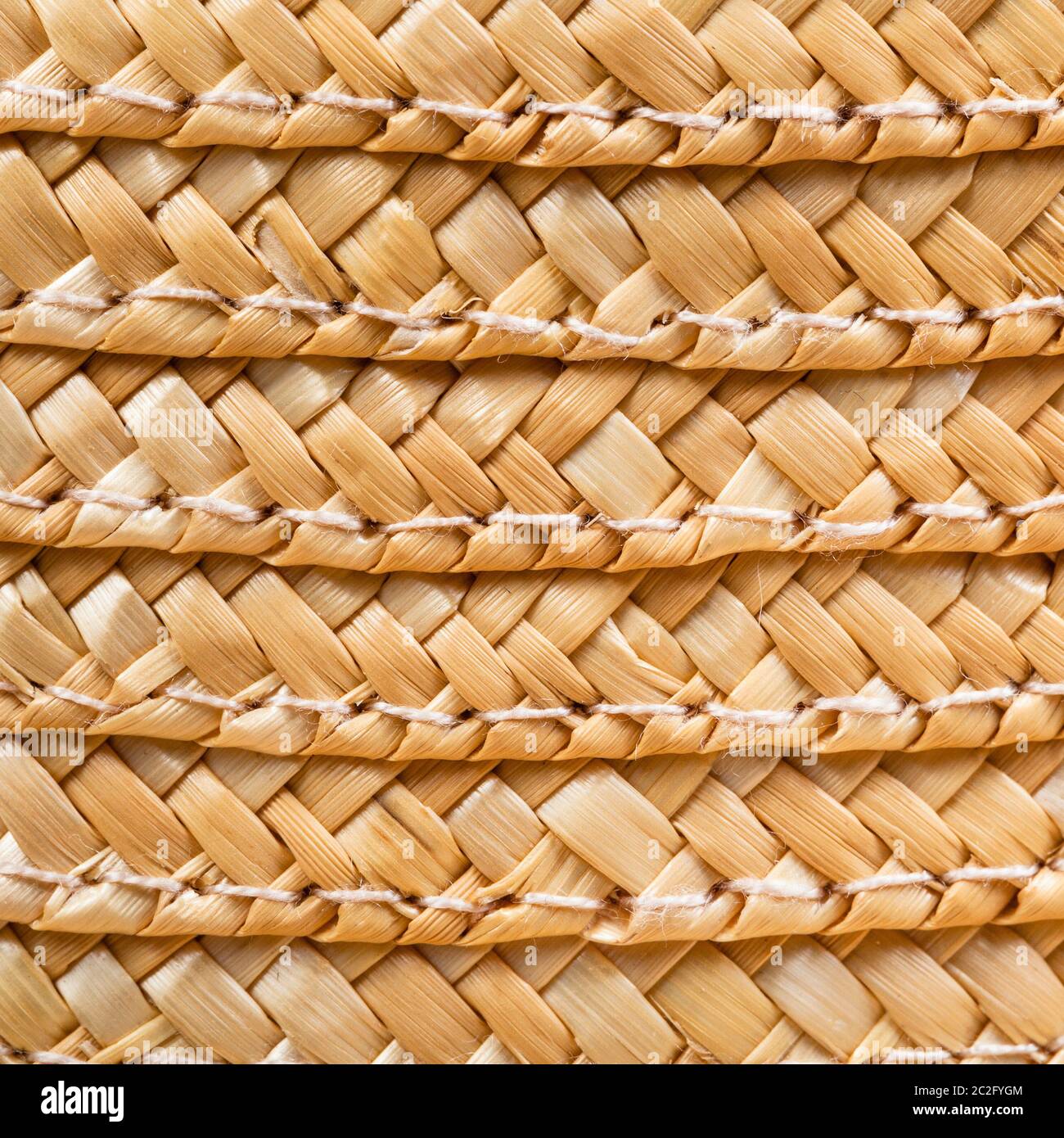 textile square background - texture of stitched summer straw hat from interwoven raffia fibers close up Stock Photo