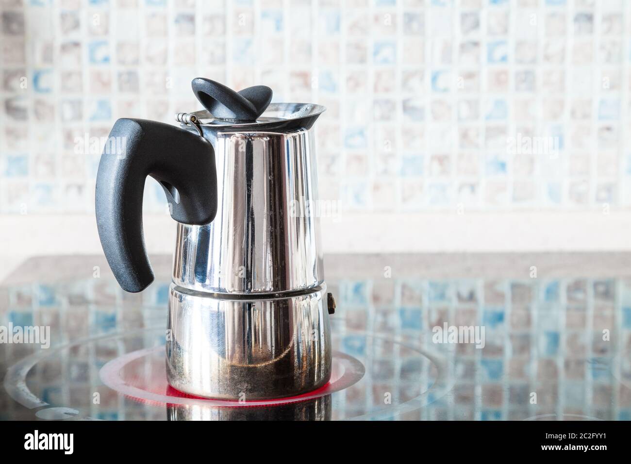 brewing coffee with pressure moka pot on ceramic electric range at home