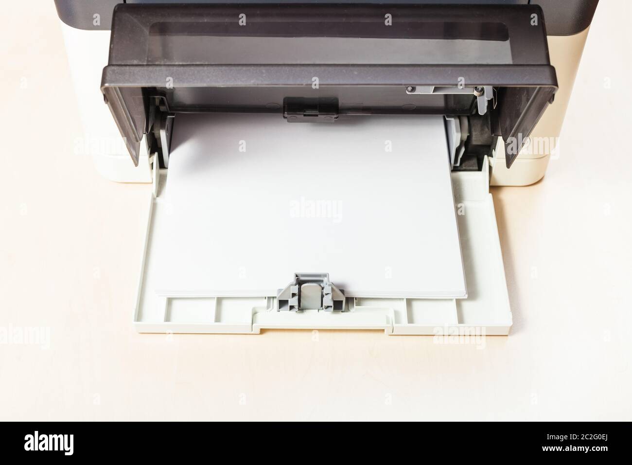 stack of white paper sheets in printer tray of multi function device on table in office Stock Photo