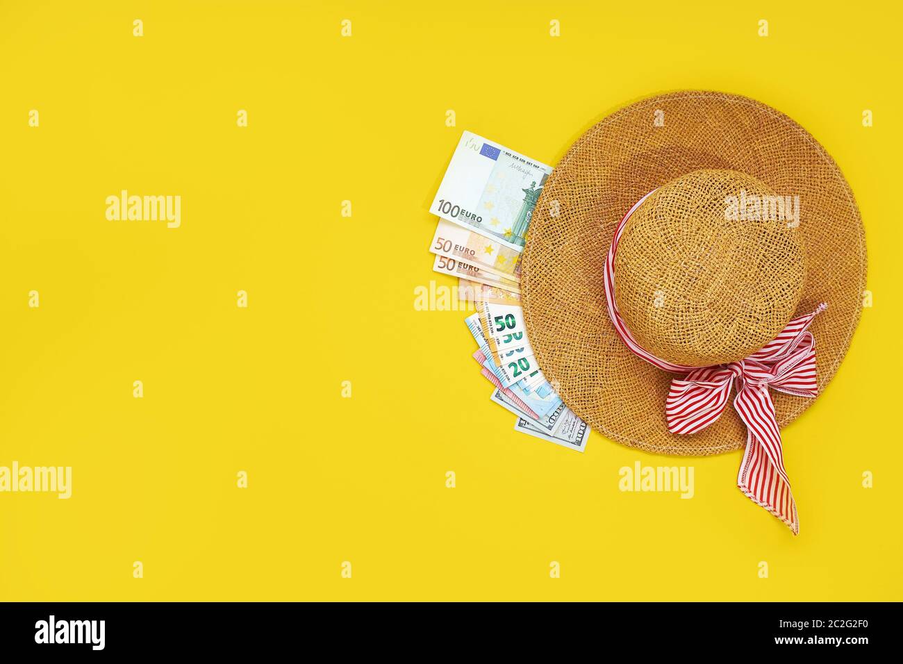 Straw hat with euro bills isolated on a yellow background. Top view flat lay. vacation cash expense concept Stock Photo