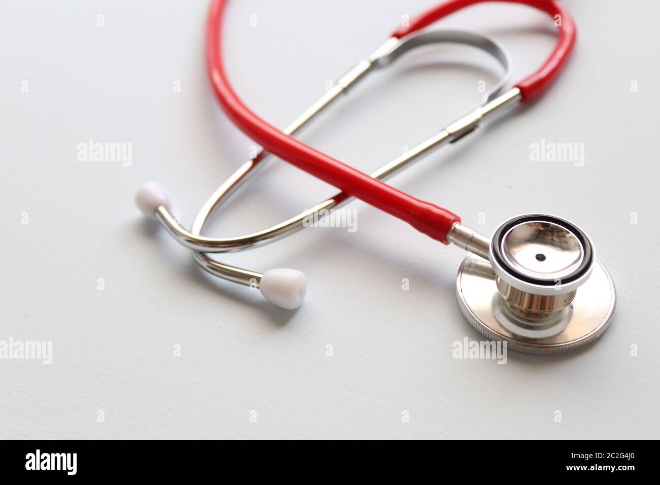 Red stethoscope on a grey background.This is an acoustic medical device for auscultation, or listening to the internal sounds of an animal or human Stock Photo