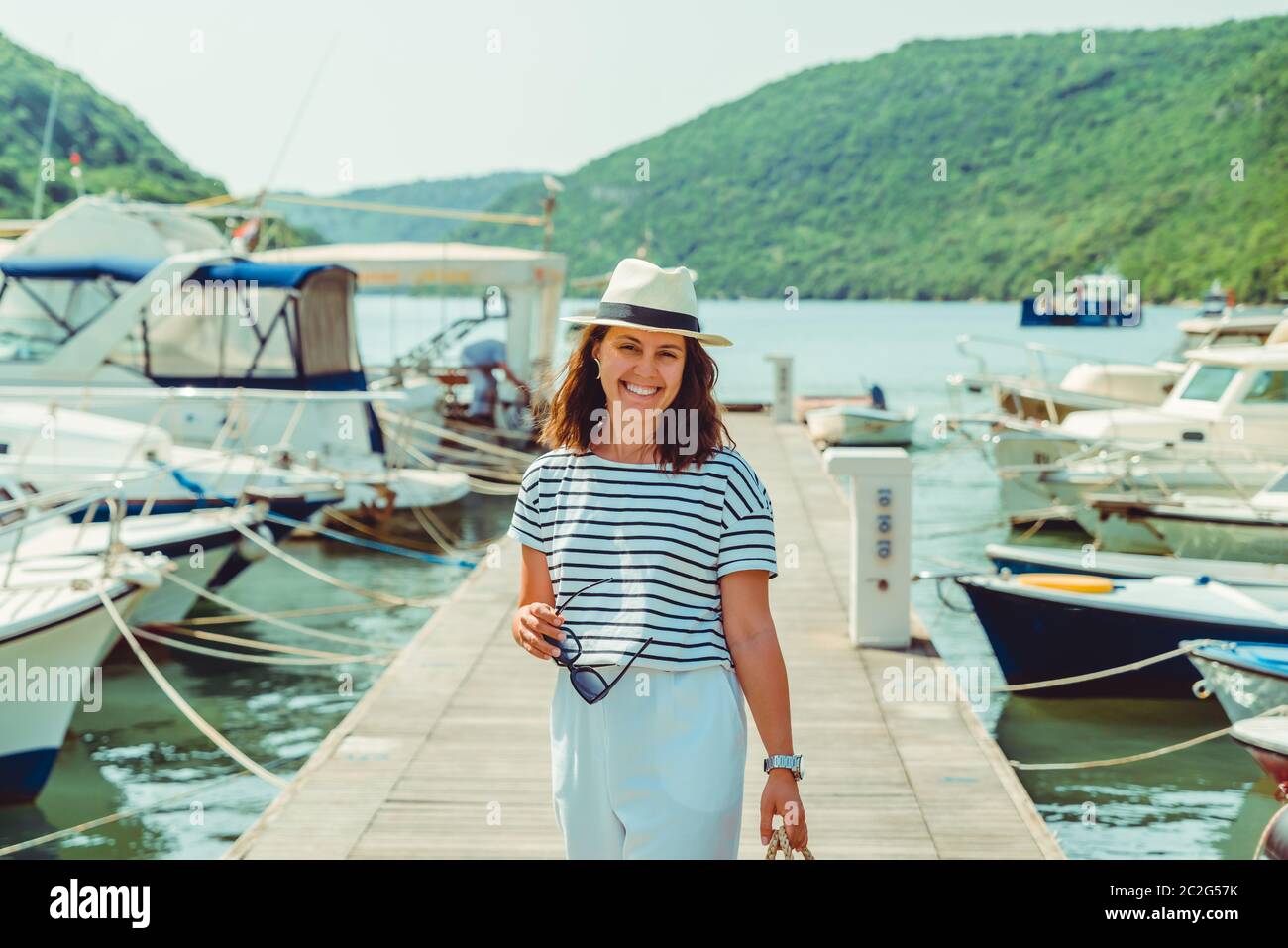 woman in white fashion luxury view walking by dock boats on background Stock Photo