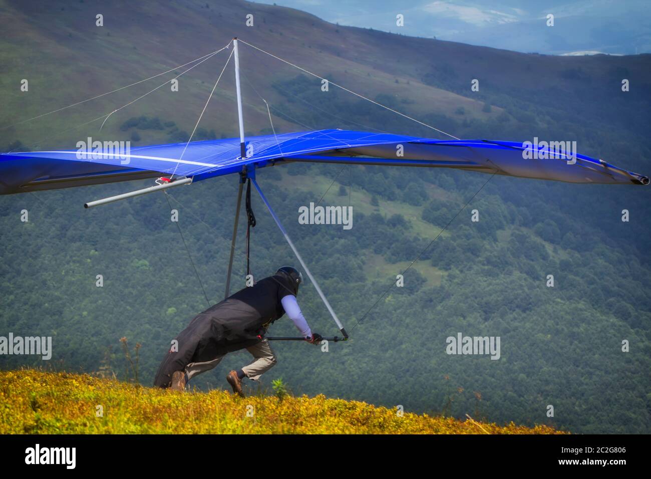 Hangglider take-off An athlete with a blue hang-glider prepares to start Stock Photo