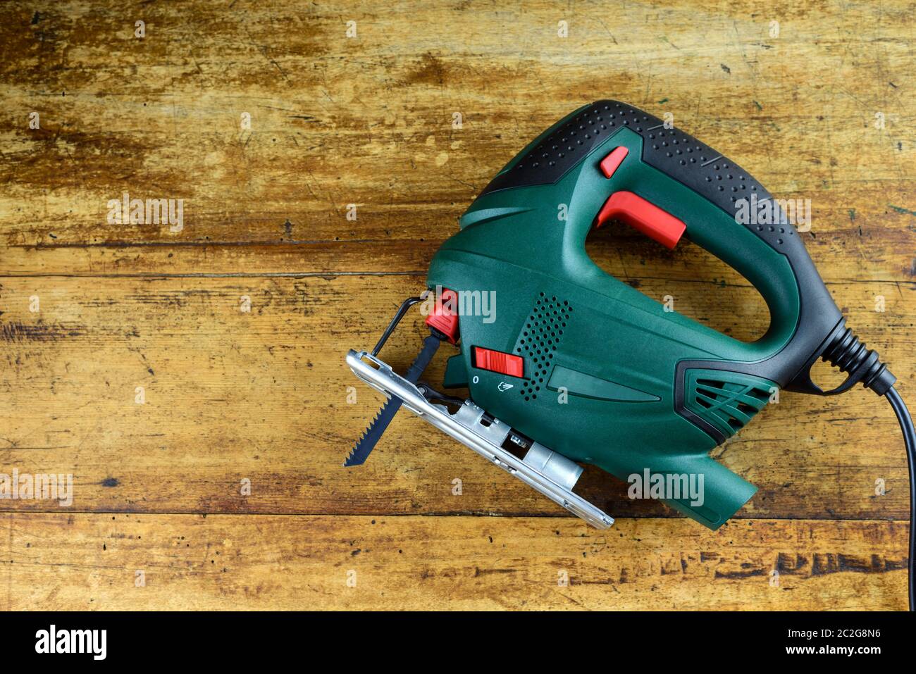 A jigsaw power tool on vintage wooden background with copy space for text. Stock Photo
