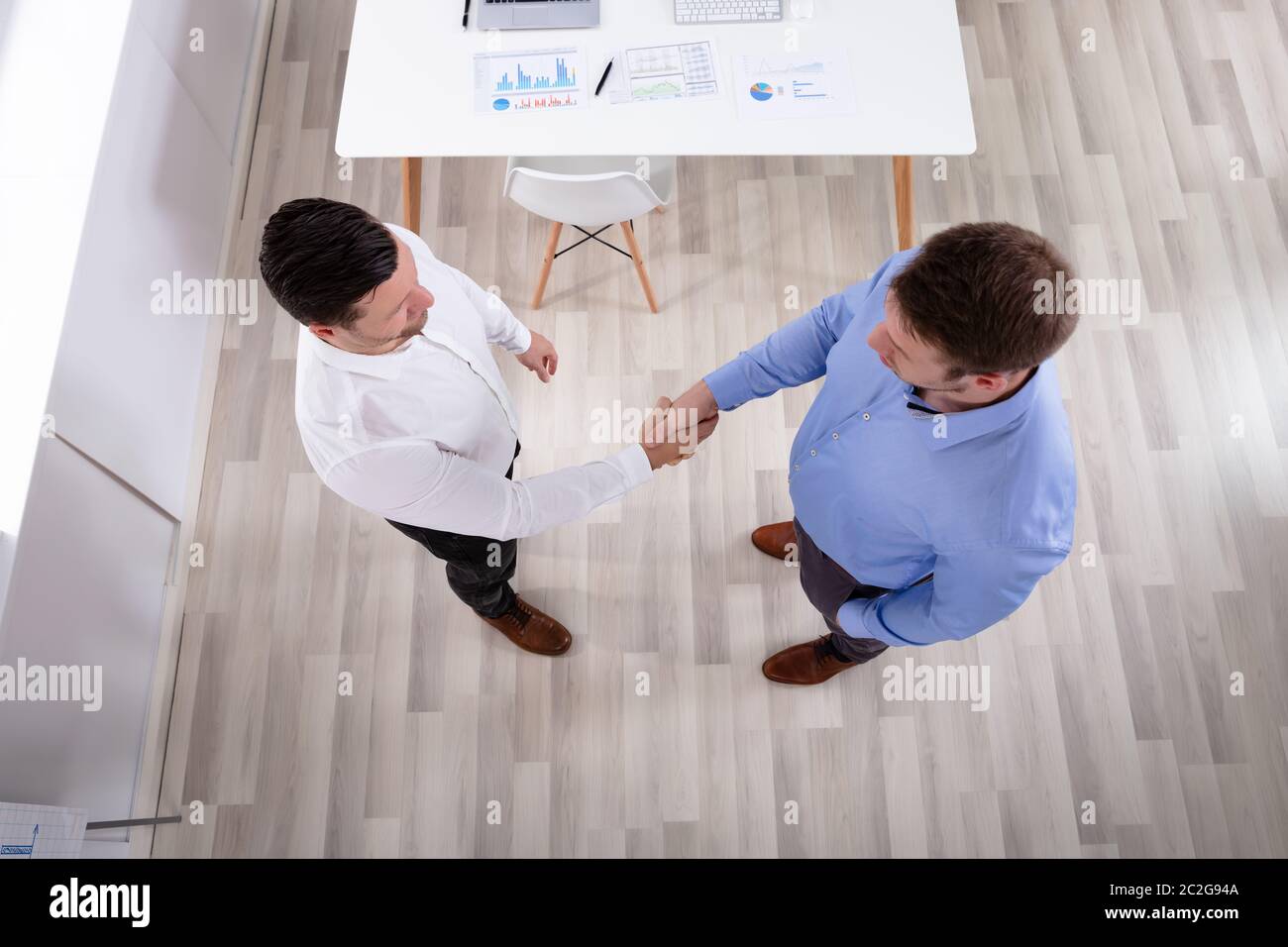 An Elevated View Of Two Businessmen Standing In The Office Shaking ...