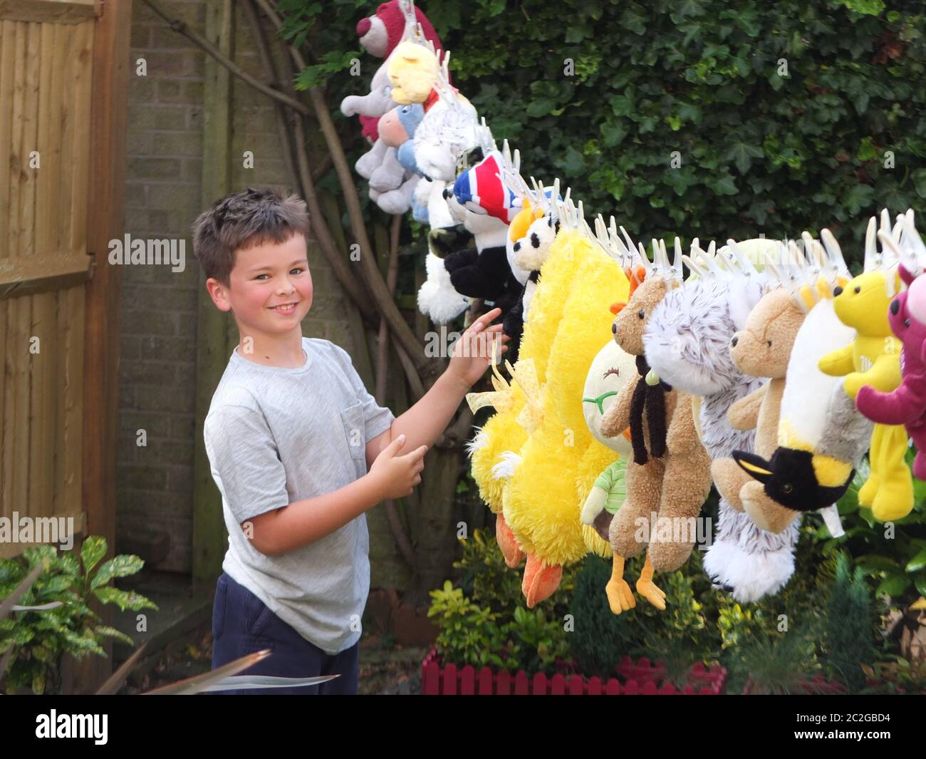 Such a happy joyous child - loads of soft toys washed and drying on the washing line for the school summer fair - very cute Stock Photo