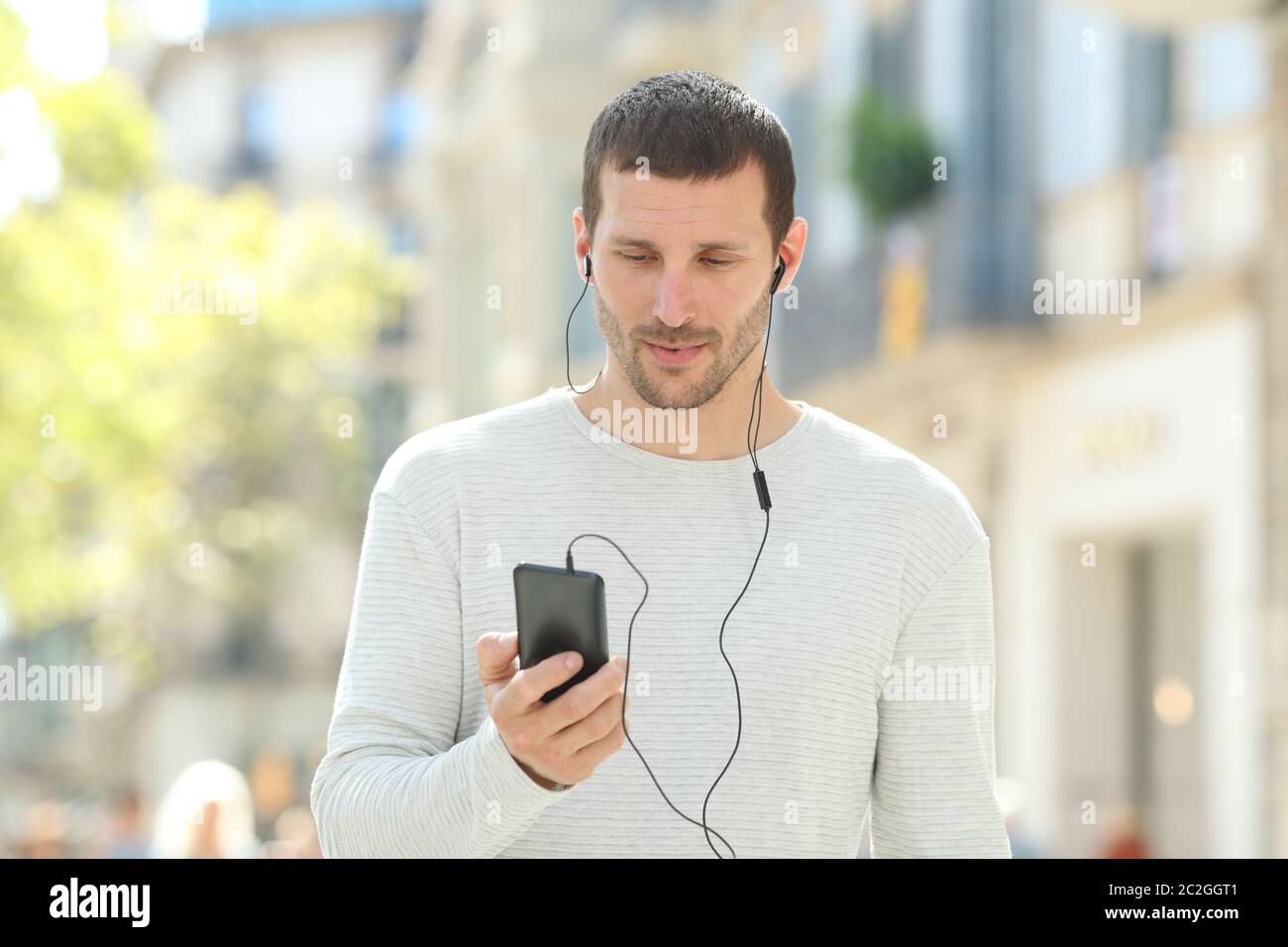 Front view portrait of a serious adult man listening to music on phone ...