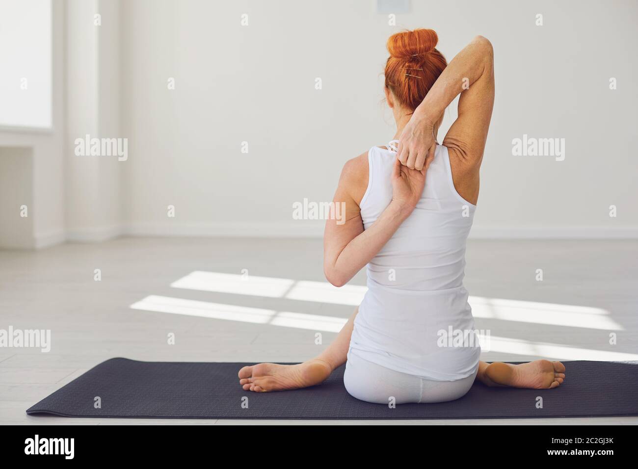 Slim woman practicing yoga in Cow Face pose Stock Photo